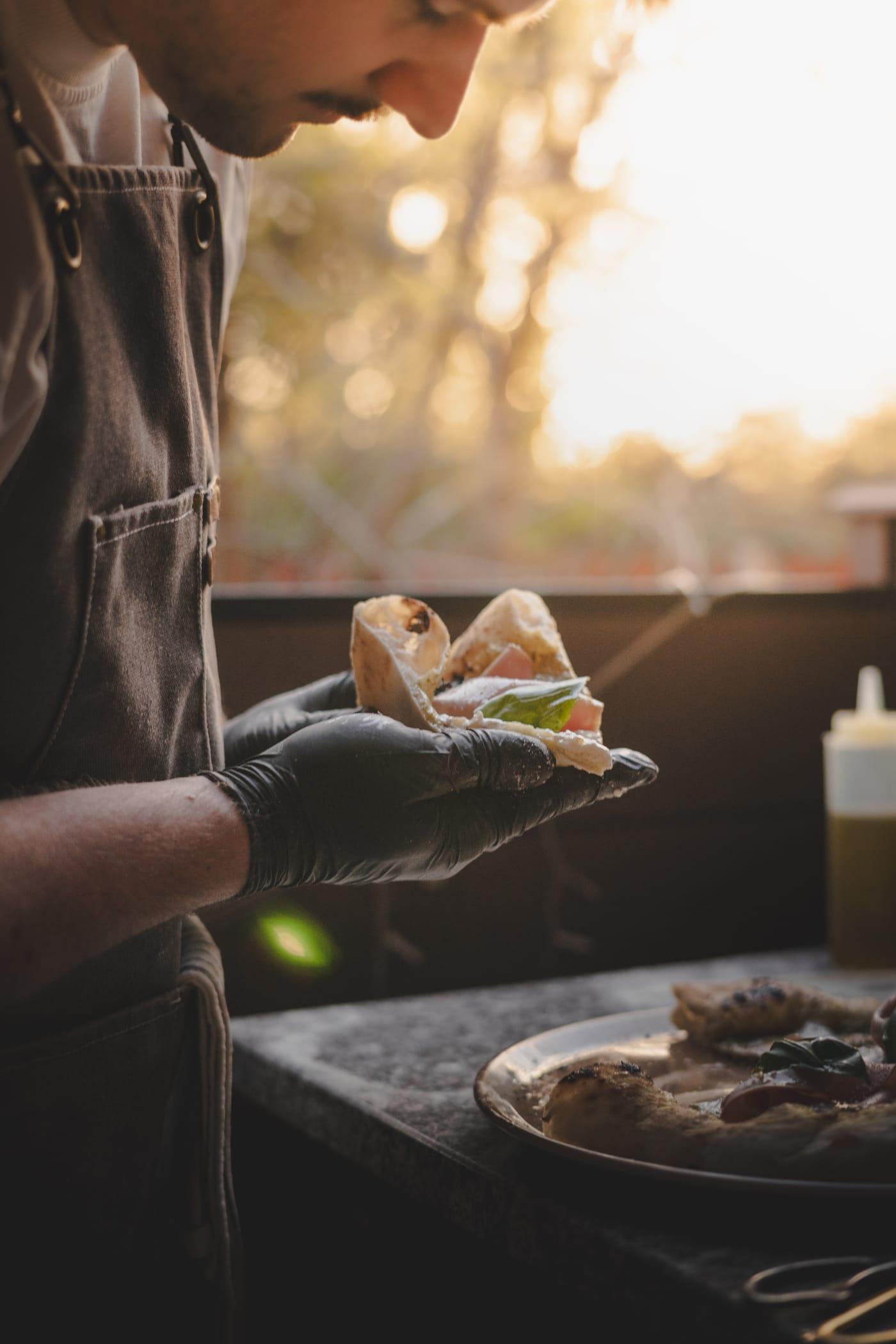Pizzaszelet a pizzaiolo kezében, ellenfényben