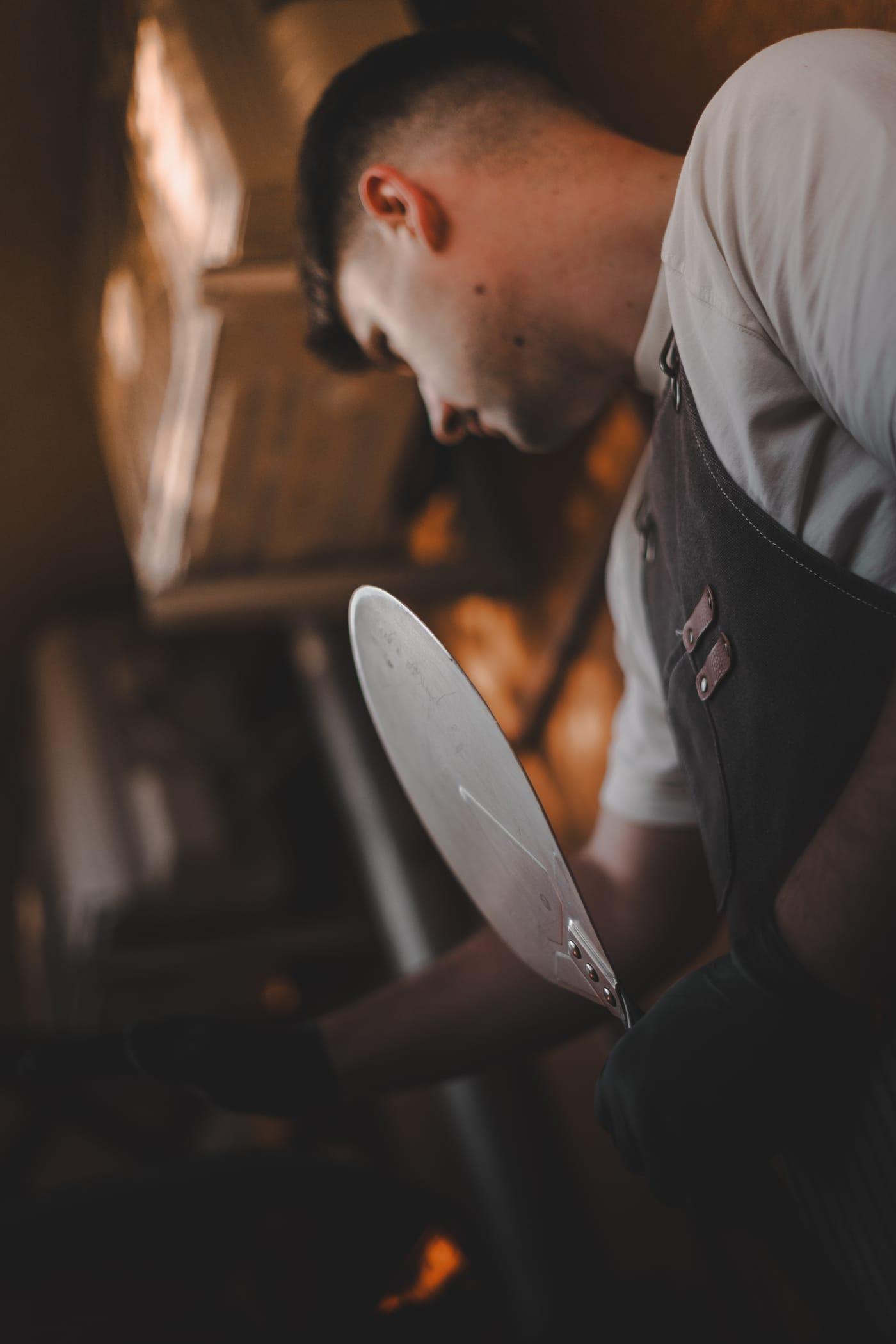 A pizzaiolo lapáttal a kemence előtt