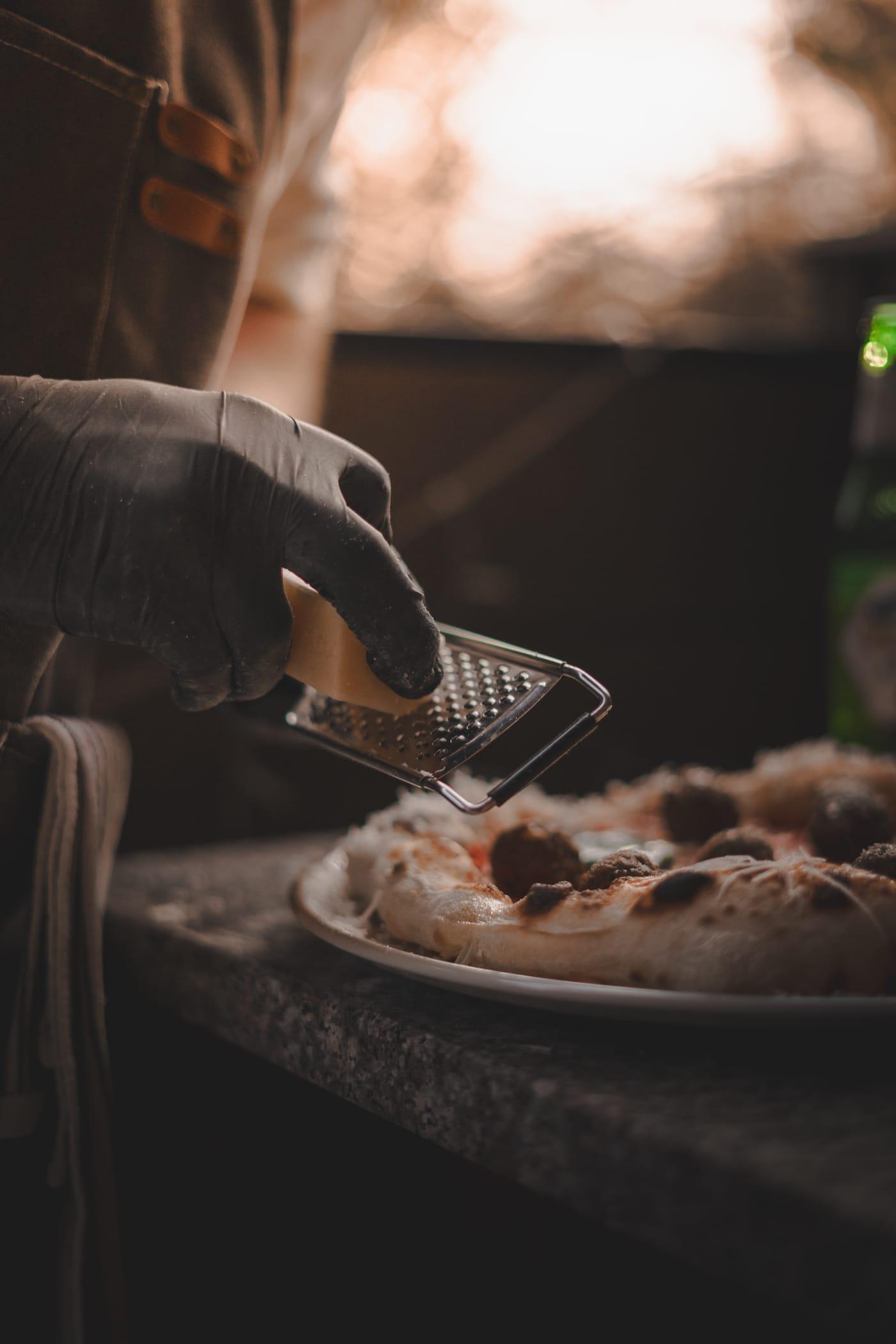 Sajt kerül a frissen sült pizzára