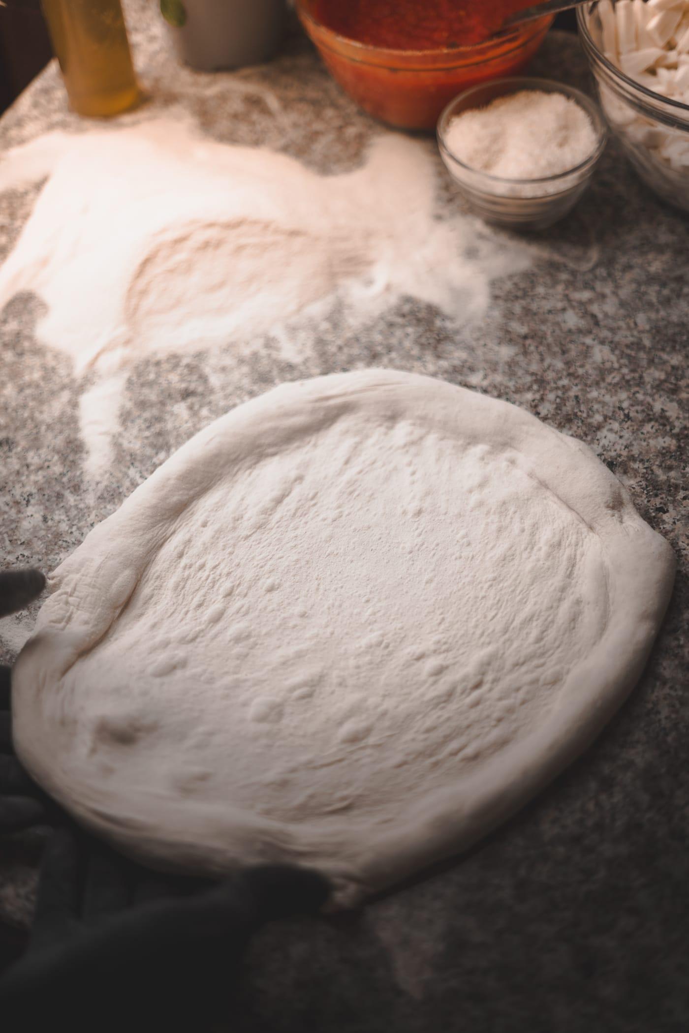 Kinyújtott pizzatészta a lisztes pulton